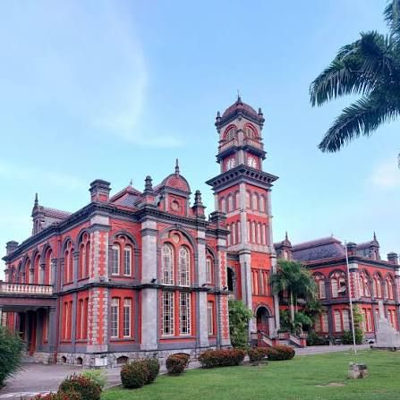 Queen's Royal College, red-and-blue German Renaissance façade with clock tower, Port of Spain